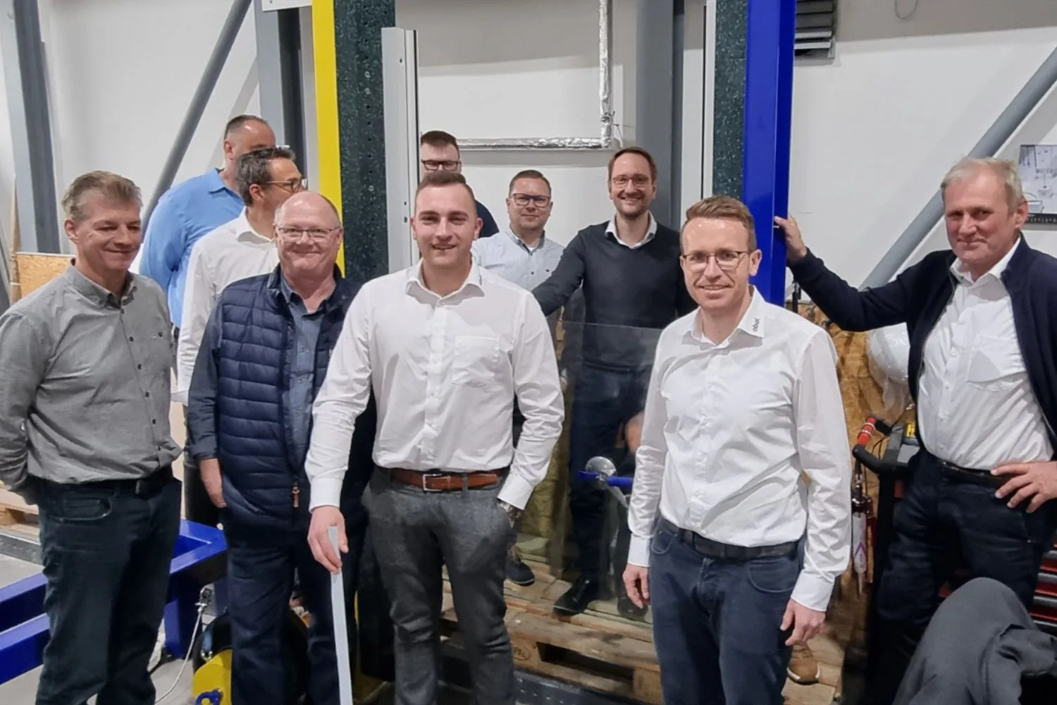 Auf dem Bild sind unsere Partner von Flachglas Sachsen zusammen mit unserem Vertriebsleiter Stefan Schmidt und Alexander Abel zu sehen. Sie stehen vor dem Prüfstand, an dem unsere Gläser für die Absturzsicherungen und Geländersysteme getestet werden.